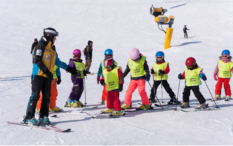 Un groupe d'enfants à ski avec un moniteur 