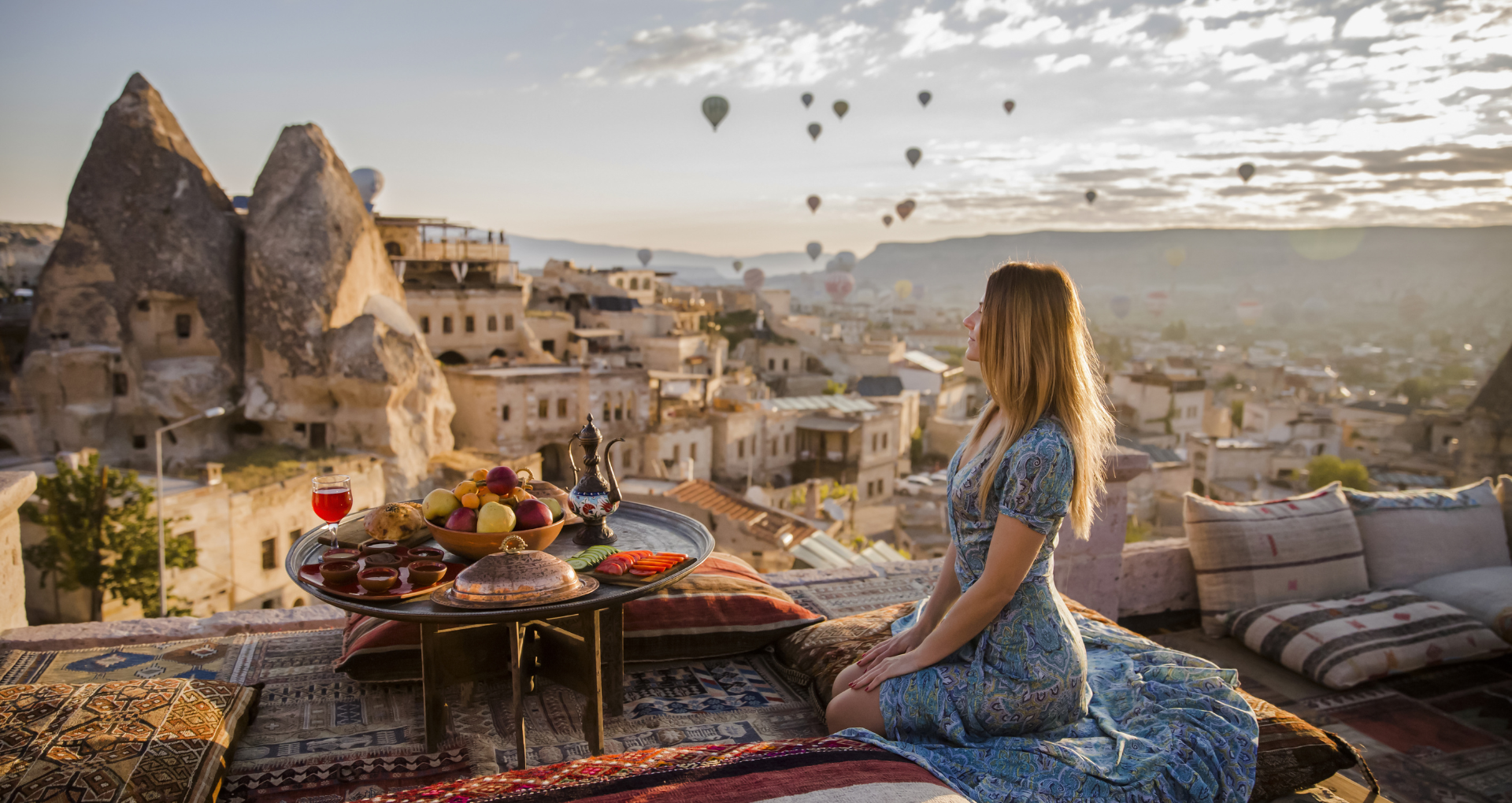 Une femme déjeunant devant un panorama avec des montgolfières en Turquie