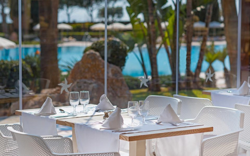 Une table de restaurant dressée pour quatre personnes, avec vue sur une piscine