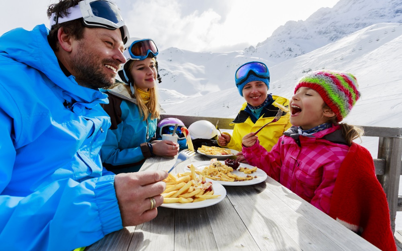 Une famille qui partage un repas au ski à table