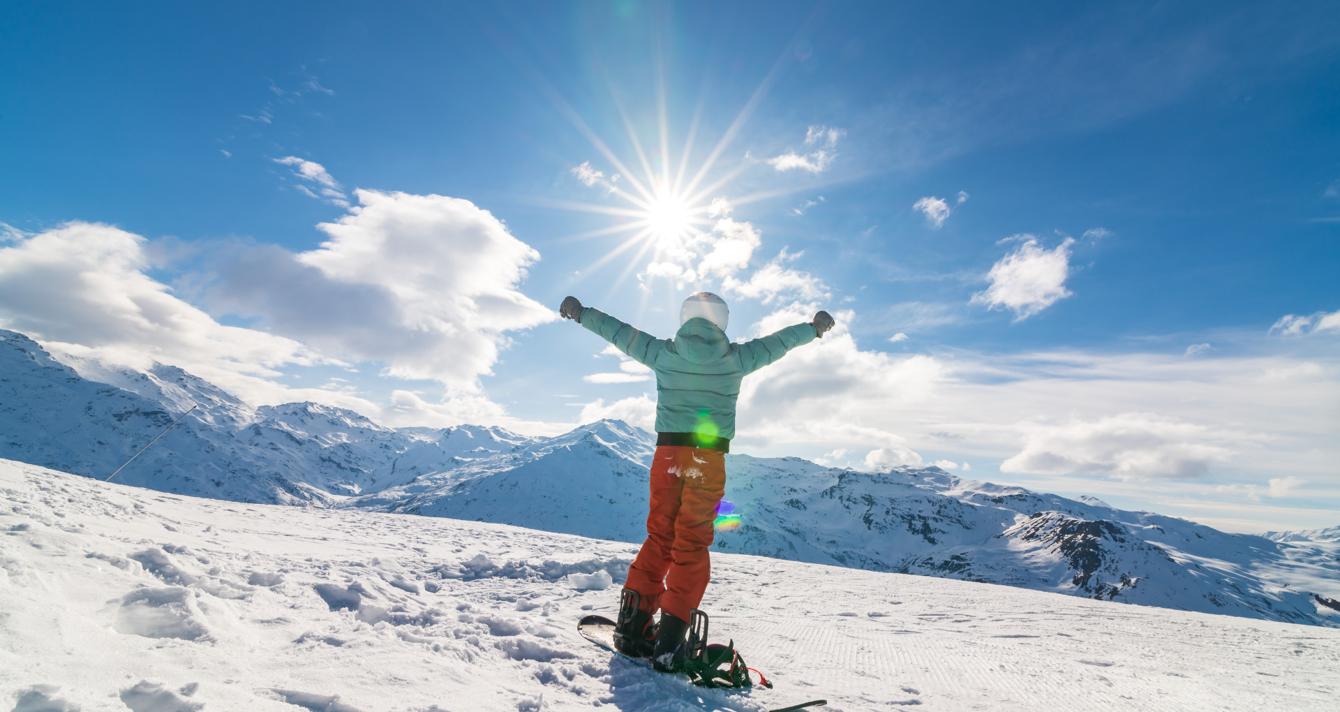 Un skieur de dos admirant la vue sur les montagnes enneigées