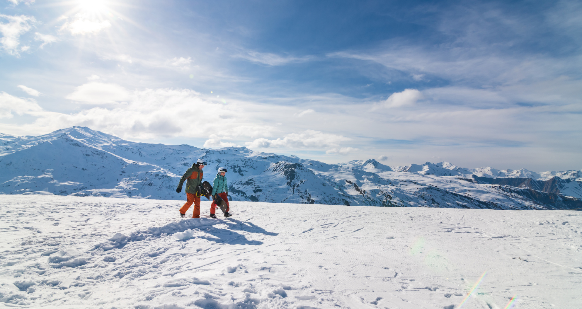 Deux skieurs marchant sur les pistes de ski avec les montagnes enneigées en arrière-plan