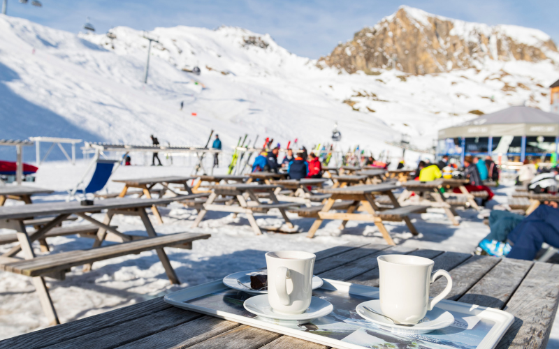 Une terrasse ensoleillée au ski avec des skieurs assis