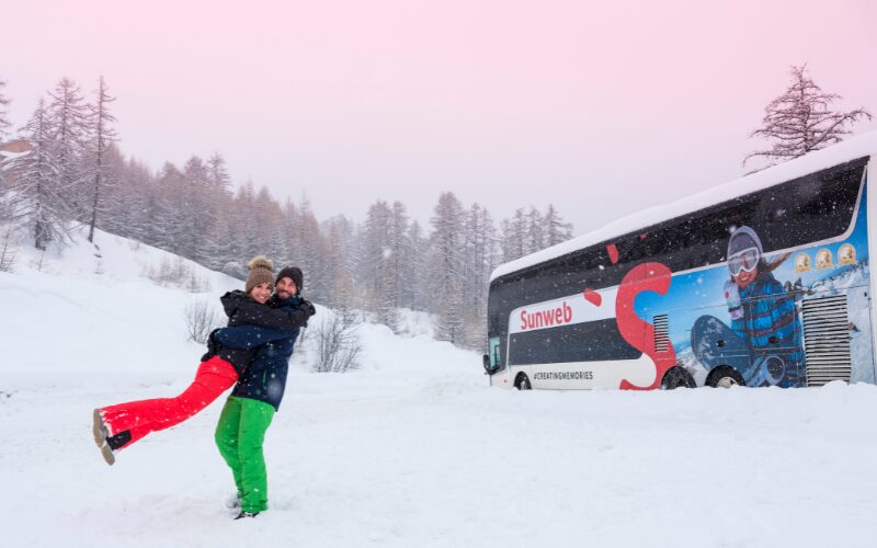 Deux skieurs qui s'enlacent face à un bus au ski